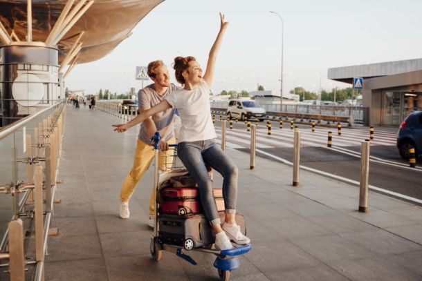Ein Paar mit einem Kofferwagen am Flughafen freut sich auf den Urlaub